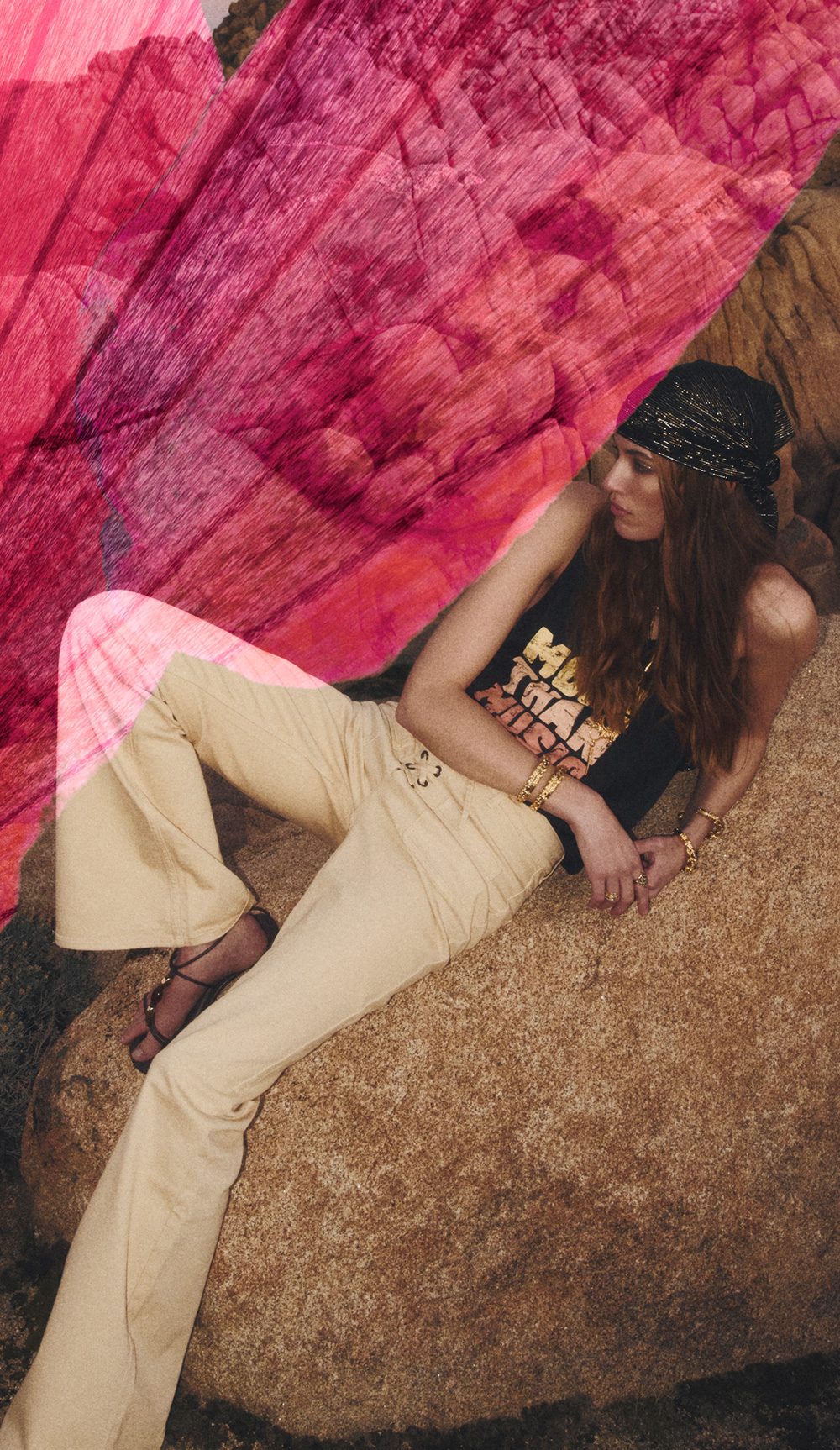 a model sitting on a rock wearing white pants and a tank top
