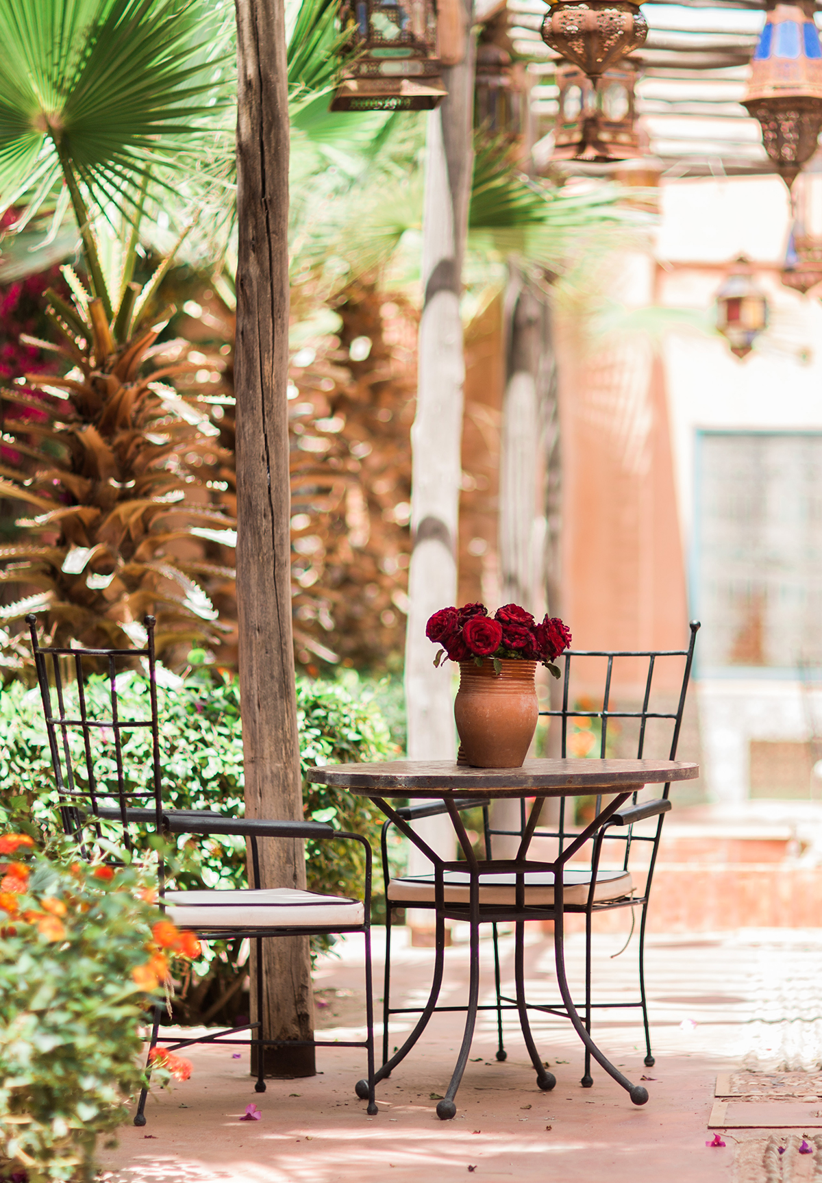An alleyway in Marrakech with a table, chairs and palm trees